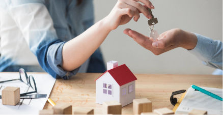 close-up-woman-s-hand-giving-house-key-man-wooden-table