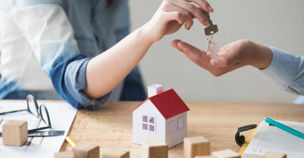 close-up-woman-s-hand-giving-house-key-manwoodentable